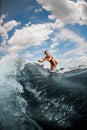 Sporty woman riding on wave sitting on surfboard against blue sky Royalty Free Stock Photo