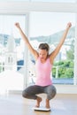 Sporty young woman crouching on weighing scale in gym Royalty Free Stock Photo