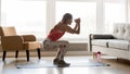 Sporty young woman doing squat morning exercise in living room