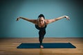 Sporty young woman doing stretching. Slim girl practicing yoga indoors on blue background. Calm, relax, healthy Royalty Free Stock Photo