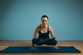 Sporty young woman doing stretching. Slim girl practicing yoga indoors on blue background. Calm, relax, healthy Royalty Free Stock Photo