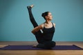 Sporty young woman doing stretching. Slim girl practicing yoga indoors on blue background. Calm, relax, healthy Royalty Free Stock Photo