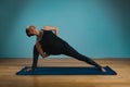 Sporty young woman doing stretching standing. Slim girl practicing yoga indoors on blue background. Calm, relax, healthy Royalty Free Stock Photo