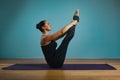 Sporty young woman doing stretching standing. Slim girl practicing yoga indoors on blue background. Calm, relax, healthy Royalty Free Stock Photo