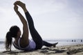 Sporty young woman doing Yoga exercises using a gym mat along the beach in Lisbon, Portugal. Playful woman working as freelance