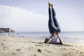 Sporty young woman doing Yoga exercises using a gym mat along the beach in Lisbon, Portugal. Playful woman working as freelance