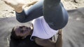 Sporty young woman doing Yoga exercises using a gym mat along the beach in Lisbon, Portugal. Playful woman working as freelance