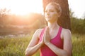 Sporty young woman leaning against a tree doing yoga exercises outdoors Royalty Free Stock Photo