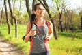 Sporty young woman listening to music while running in park Royalty Free Stock Photo