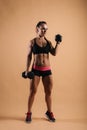 Sporty young woman with perfect muscular body is posing with two dumbbells Royalty Free Stock Photo