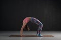 Woman practices yoga asana chakrasana or urdva dhanurasana or wheel pose