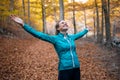 Sporty young woman with raised up hands enjoying the nature in the park in the autumn morning Royalty Free Stock Photo