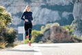 Sporty young woman running on mountain road in beautiful nature