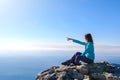 Sporty young woman sitting in a rocky top of the mountain against the blue of sky and sea Royalty Free Stock Photo