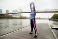 Sporty young woman in in sportswear doing stretching exercises on a wooden pier near the river Royalty Free Stock Photo