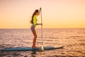 Sporty young woman at stand up paddle board with beautiful sunset colors Royalty Free Stock Photo