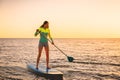 Attractive young woman at stand up paddle board with sunset colors Royalty Free Stock Photo
