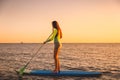 Sporty woman at stand up paddle board with colorful sunset colors Royalty Free Stock Photo