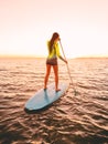 Sporty young woman at stand up paddle board with bright sunset colors Royalty Free Stock Photo