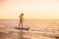 Sporty young woman stand up paddle surfing with beautiful sunset or sunrise colors Royalty Free Stock Photo