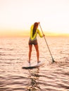 Sporty young woman stand up paddle surfing with beautiful sunset or sunrise colors Royalty Free Stock Photo