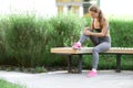 Sporty young woman suffering from knee pain while sitting on wooden bench in park Royalty Free Stock Photo