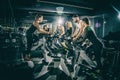 Sporty young women and men riding exercise bikes on cycling class with assistance of female instructor in the gym Royalty Free Stock Photo