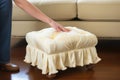 spot-cleaning a tufted cream ottoman with a cloth