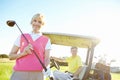Spot of golf. Low angle shot of an attractive older female golfer standing in front of a golf cart with her golfing Royalty Free Stock Photo