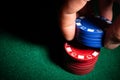 Spot light of hand putting down cashino chips on green table Royalty Free Stock Photo