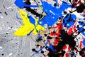 A spot of white and black and yellow and green and red and blue spilled paint on a concrete textured surface Royalty Free Stock Photo