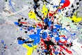 A spot of white and black and yellow and green and red and blue spilled paint on a concrete textured surface Royalty Free Stock Photo