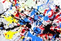 A spot of white and black and yellow and green and red and blue spilled paint on a concrete textured surface Royalty Free Stock Photo