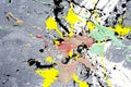 A spot of white and black and yellow and green and red spilled paint on a concrete textured surface Royalty Free Stock Photo