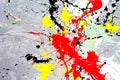 A spot of white and black and yellow and green and red spilled paint on a concrete textured surface Royalty Free Stock Photo