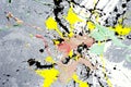 A spot of white and black and yellow and green and red spilled paint on a concrete textured surface Royalty Free Stock Photo