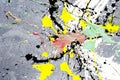 A spot of white and black and yellow and green and red spilled paint on a concrete textured surface Royalty Free Stock Photo