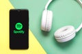 Spotify logo on black screen of smartphone with white headphones