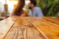 spotless wood table, blurred couple enjoying drinks behind