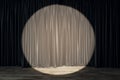 Spotlight on taupe curtains against a dark backdrop, theatrical stage setting. Royalty Free Stock Photo