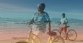 Spots of light against african american senior couple with bicycles walking together at the beach Royalty Free Stock Photo