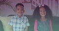 Spots of light against portrait of african american brother and sister smiling sitting on the couch Royalty Free Stock Photo