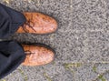 Looking down at spots on men`s brown leather dress shoes after wet from rain