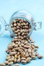 Spotty red beans spilled out of a glass jar on a blue background. Close-up Royalty Free Stock Photo