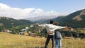 spouses, tourists stop on a high mountain, arms wide open, look with admiration at the resort town of Jermuk