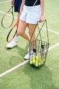 Spouses walk with rackets and basket of balls on tennis court Royalty Free Stock Photo