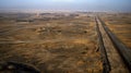 A sprawling network of pipelines crisscrossing the desolate landscape with gas flares visible at regular intervals