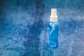 Spray bottle with blue liquid inside on blue grunge backdrop in selective focus Royalty Free Stock Photo