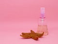 A spray bottle filled with liquid and a starfish on a pink background Royalty Free Stock Photo