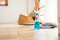 Spray bottle in a side view with blue liquid detergent inside on the wooden floor with rag and grey feather duster in an empty Royalty Free Stock Photo
